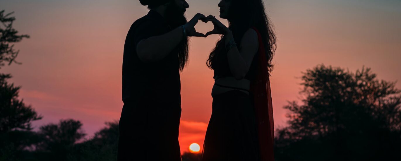 silhouette photo of couple making a heart shape