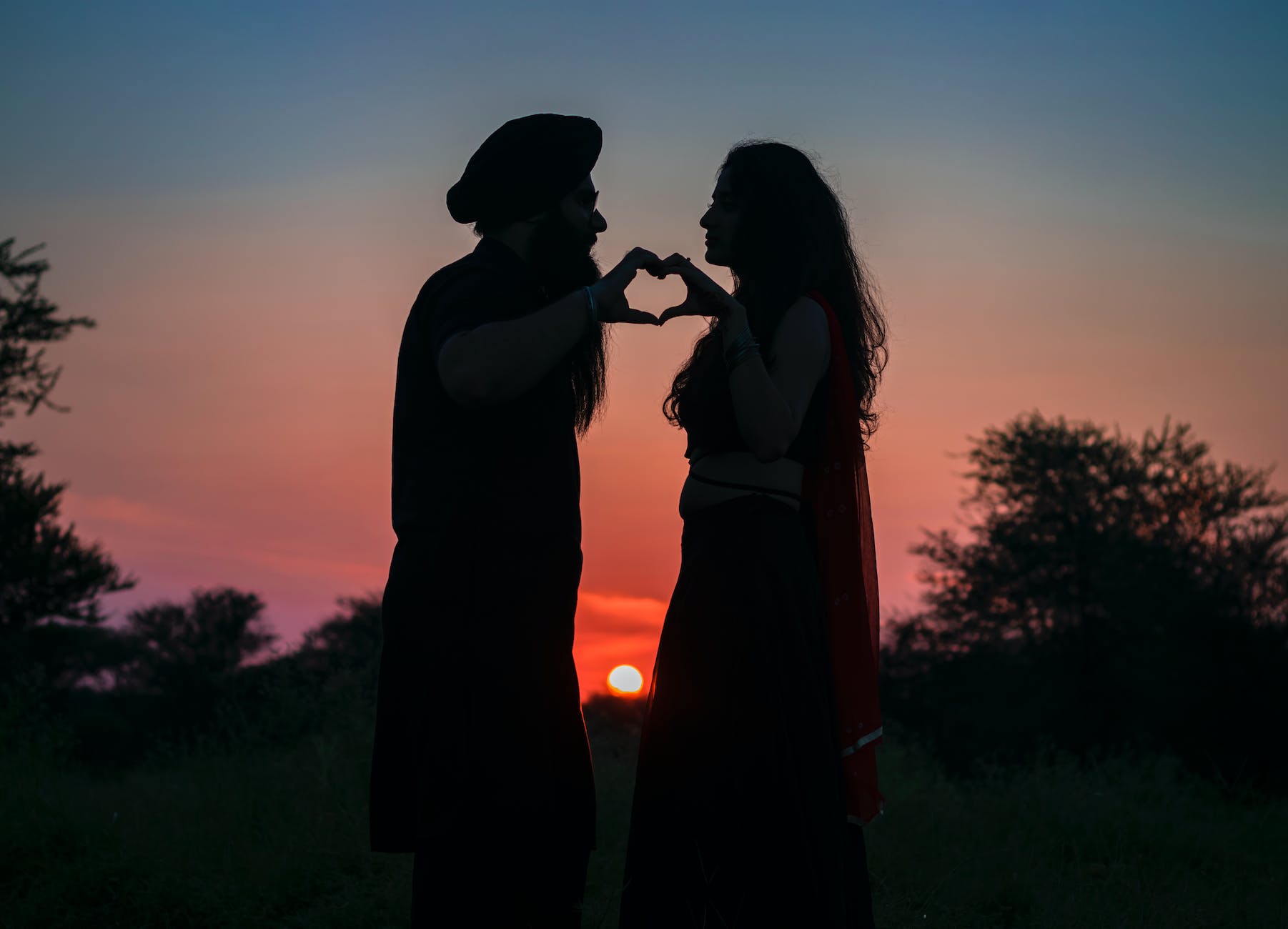 silhouette photo of couple making a heart shape