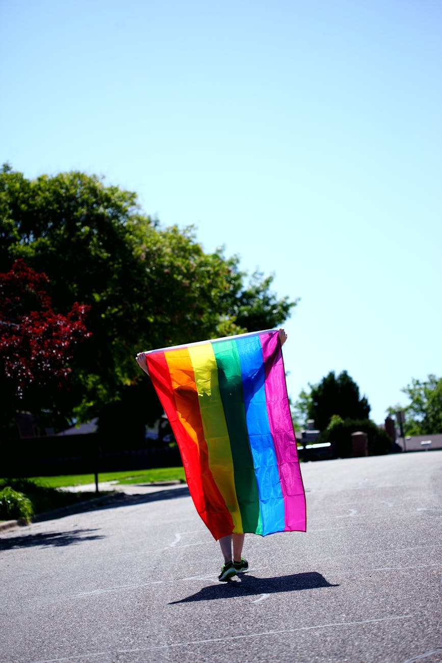 person walking while holding rainbow colored flag