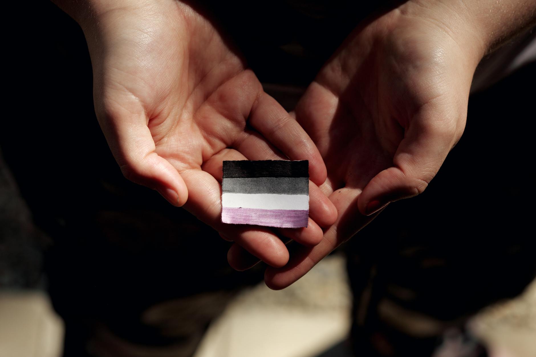 hands holding flag asexual symbol