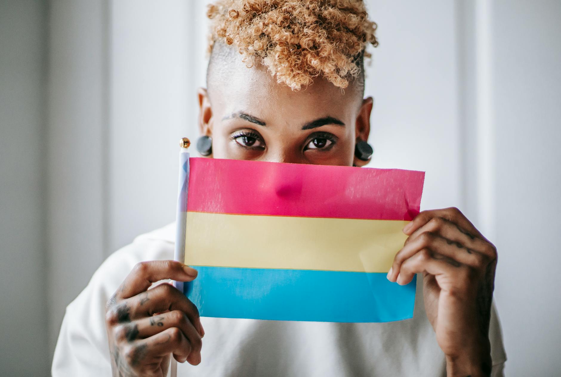 black tattooed woman showing pansexual pride flag